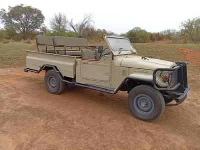a tan truck parked on a dirt road at River Ridge Log Home - Inside Dinokeng Big 5 in Klipdrift