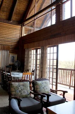 a living room with chairs and a table and windows at River Ridge Log Home - Inside Dinokeng Big 5 in Klipdrift