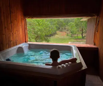 a child laying in a bath tub with a window at Wit Hangmat Bush Retreat in Sybrandskraal