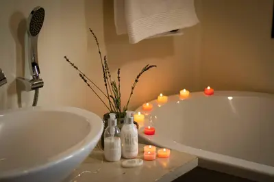 a bathroom with a tub and candles on a counter at Wit Hangmat Bush Retreat in Sybrandskraal