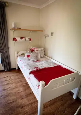 a small bedroom with a white bed with red sheets at Wit Hangmat Bush Retreat in Sybrandskraal