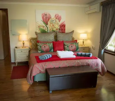 a bedroom with a large bed with red and green pillows at Wit Hangmat Bush Retreat in Sybrandskraal