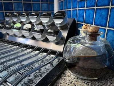 a glass bottle on a counter next to a row of utensils at Wit Hangmat Bush Retreat in Sybrandskraal