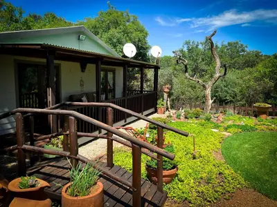 a house with a porch and a garden with plants at Wit Hangmat Bush Retreat in Sybrandskraal