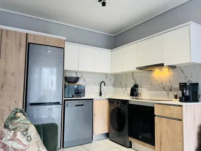 a kitchen with white cabinets and stainless steel appliances at Playa Azul in Pretoria