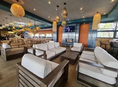 a bar with white couches and a restaurant at Playa Azul in Pretoria