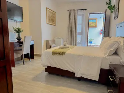 a bedroom with a bed and a desk and a computer at Miyanwe Guest House - Waterkloof in Pretoria