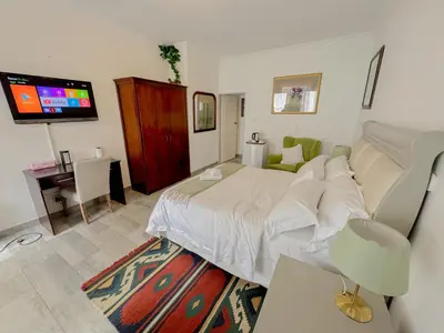 a bedroom with a bed and a flat screen tv at Miyanwe Guest House - Waterkloof in Pretoria