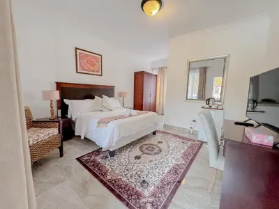 a bedroom with a bed and a mirror and a tv at Miyanwe Guest House - Waterkloof in Pretoria