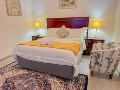 a bedroom with a large bed and a chair at Miyanwe Guest House - Waterkloof in Pretoria