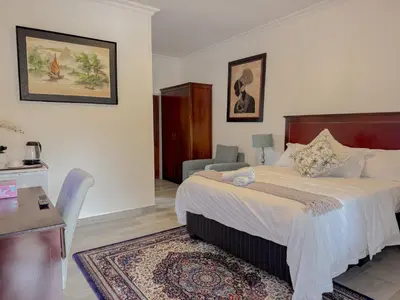 a bedroom with a bed and a table and a chair at Miyanwe Guest House - Waterkloof in Pretoria