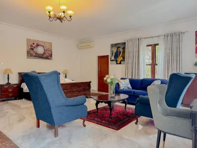 a living room with blue chairs and a table at Miyanwe Guest House - Waterkloof in Pretoria