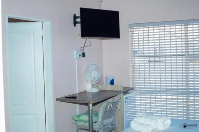 a room with a desk with a fan and a window at Emmanuel Guesthouse in Witbank