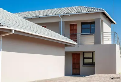 a white house with a balcony on top of it at Emmanuel Guesthouse in Witbank