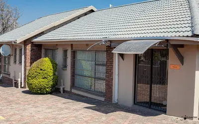 a brick house with a garage with a door at Emmanuel Guesthouse in Witbank