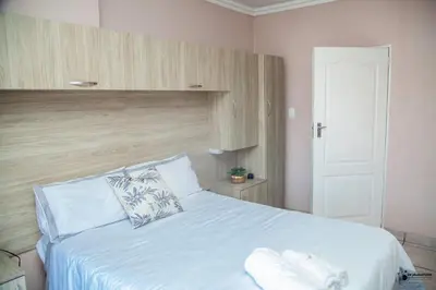 a bedroom with a bed with white sheets and a door at Emmanuel Guesthouse in Witbank