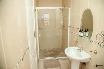 a bathroom with a shower and a toilet and a sink at Emmanuel Guesthouse in Witbank