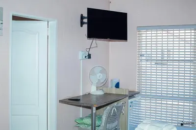 a room with a desk with a fan and a window at Emmanuel Guesthouse in Witbank