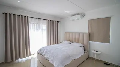 a bedroom with a bed and a large window at Away like Home in Midrand