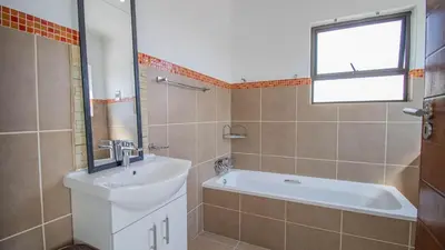 a bathroom with a sink and a tub and a window at Away like Home in Midrand