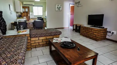 a living room with a couch and a tv at Hoogland Spa Resort Bela Bela in Bela-Bela