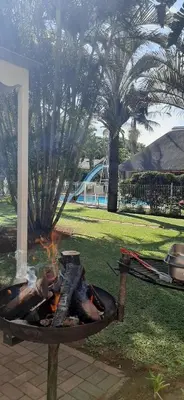a fire pit in a park with trees in the background at Hoogland Spa Resort Bela Bela in Bela-Bela