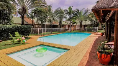 a large swimming pool in a yard with palm trees at Hoogland Spa Resort Bela Bela in Bela-Bela