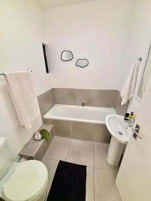 a bathroom with a tub and a toilet and a sink at Waterfall Smart Apartment in Midrand