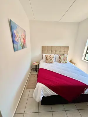 a bedroom with a large bed with a red blanket at Waterfall Smart Apartment in Midrand