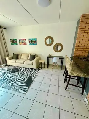 a living room with a couch and a table at Waterfall Smart Apartment in Midrand