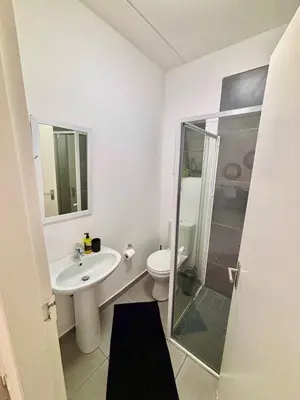 a bathroom with a toilet and a sink and a shower at Waterfall Smart Apartment in Midrand