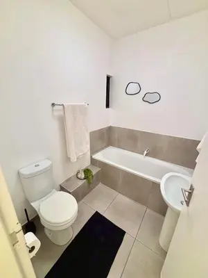 a bathroom with a toilet and a tub and a sink at Waterfall Smart Apartment in Midrand
