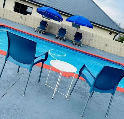 a table and chairs and umbrellas next to a swimming pool at The Perazim Place at 222 Sabie River Eco-Estate in Hazyview