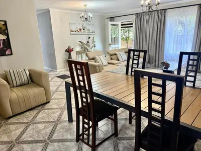 a dining room and living room with a table and chairs at Marie Guest House in Polokwane