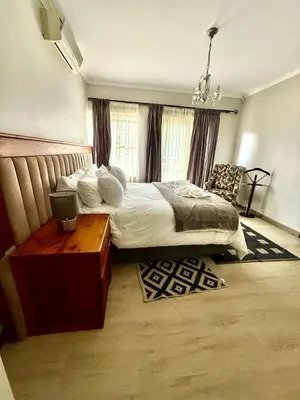 a bedroom with a large bed and a table at Marie Guest House in Polokwane