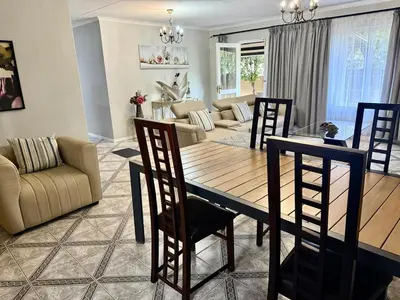a dining room and living room with a table and chairs at Marie Guest House in Polokwane