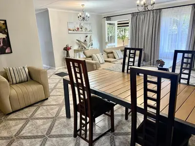 a dining room and living room with a table and chairs at Marie Guest House in Polokwane