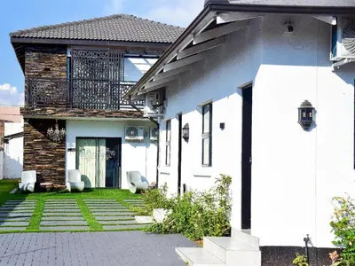 a white house with two chairs in a yard at C'est La Vie Guest House in Witbank