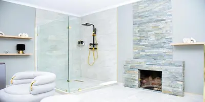 a bathroom with a glass shower with a fireplace at C'est La Vie Guest House in Witbank