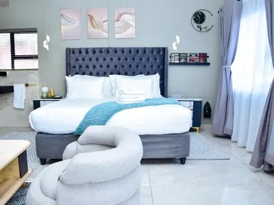 a bedroom with a large bed and a chair at C'est La Vie Guest House in Witbank