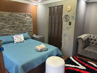 a bedroom with a blue bed and a chair at Lakeboutiquehotel empire new in Thohoyandou