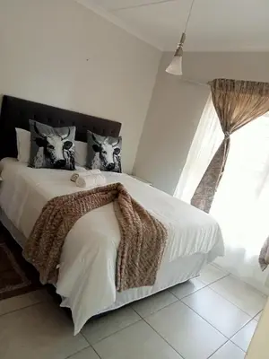 a bedroom with a bed with white sheets and a window at kaso holidays at the Blyde in Pretoria