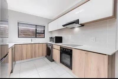 a kitchen with white appliances and wooden cabinets at kaso holidays at the Blyde in Pretoria