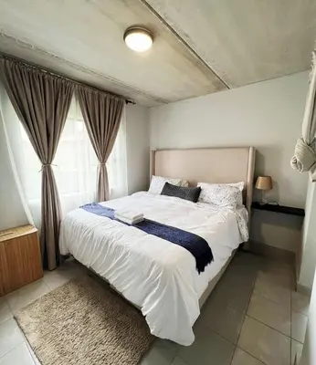a bedroom with a large white bed with a window at Felinga Guest House in Centurion