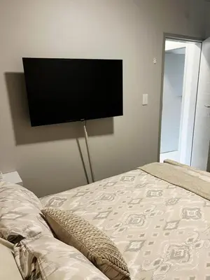 a bedroom with a flat screen tv on the wall at Felinga Guest House in Centurion