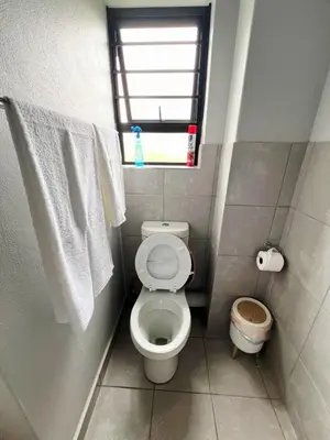 a small bathroom with a toilet and a window at Felinga Guest House in Centurion