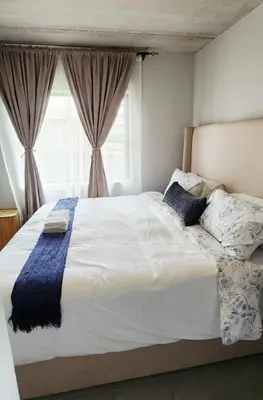a bedroom with a large white bed with a window at Felinga Guest House in Centurion