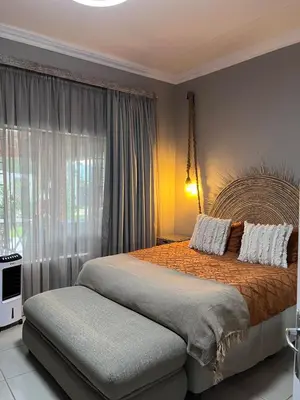 a bedroom with a large bed and a window at Blessings is a home with Cozy Charms in Pretoria