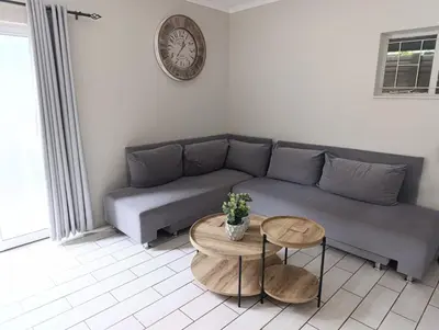 a living room with a couch and a clock on the wall at Joy Haven - Cottage in Centurion