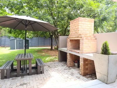 a patio with an umbrella and a brick oven at Joy Haven - Cottage in Centurion